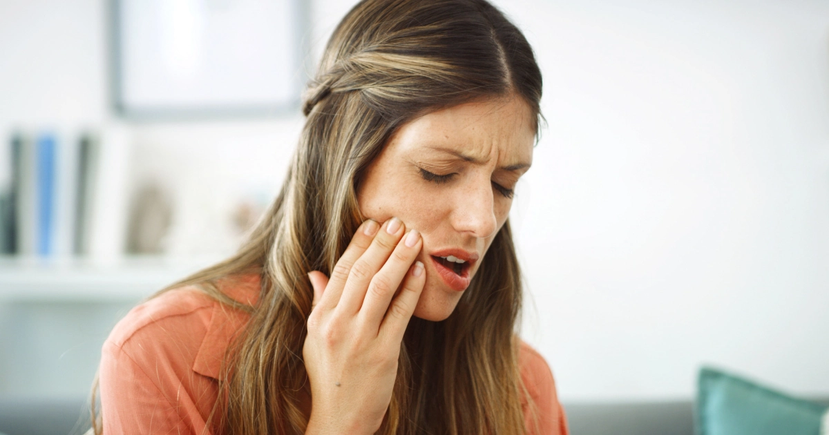 A woman holding her cheek in discomfort, often seen by a Gum Disease Dentist in Phoenix, AZ.