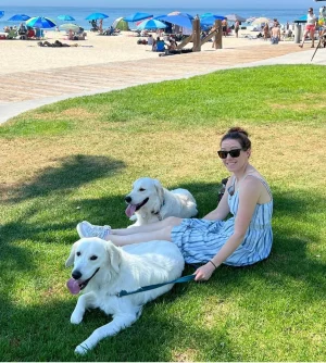 Woman sitting on grass with two dogs on a beach | 24th Street Dental Biltmore in Phoenix, AZ