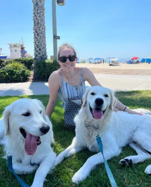 Woman sitting on grass with two dogs on a beach | 24th Street Dental Biltmore in Phoenix, AZ